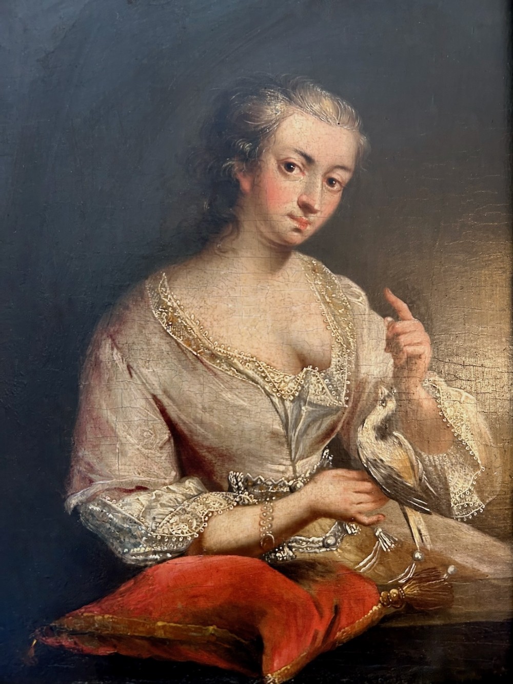 An antique oil portrait depicting a woman in 18th-century dress holding a small bird, set within a deeply moulded gold giltwood frame. View V