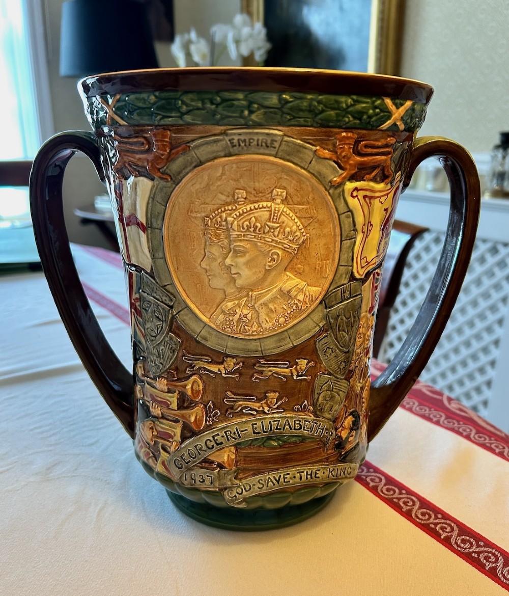 A brown glazed earthenware twin-handled loving cup featuring relief-moulded profile portraits of King George VI and Queen Elizabeth dated 1937.