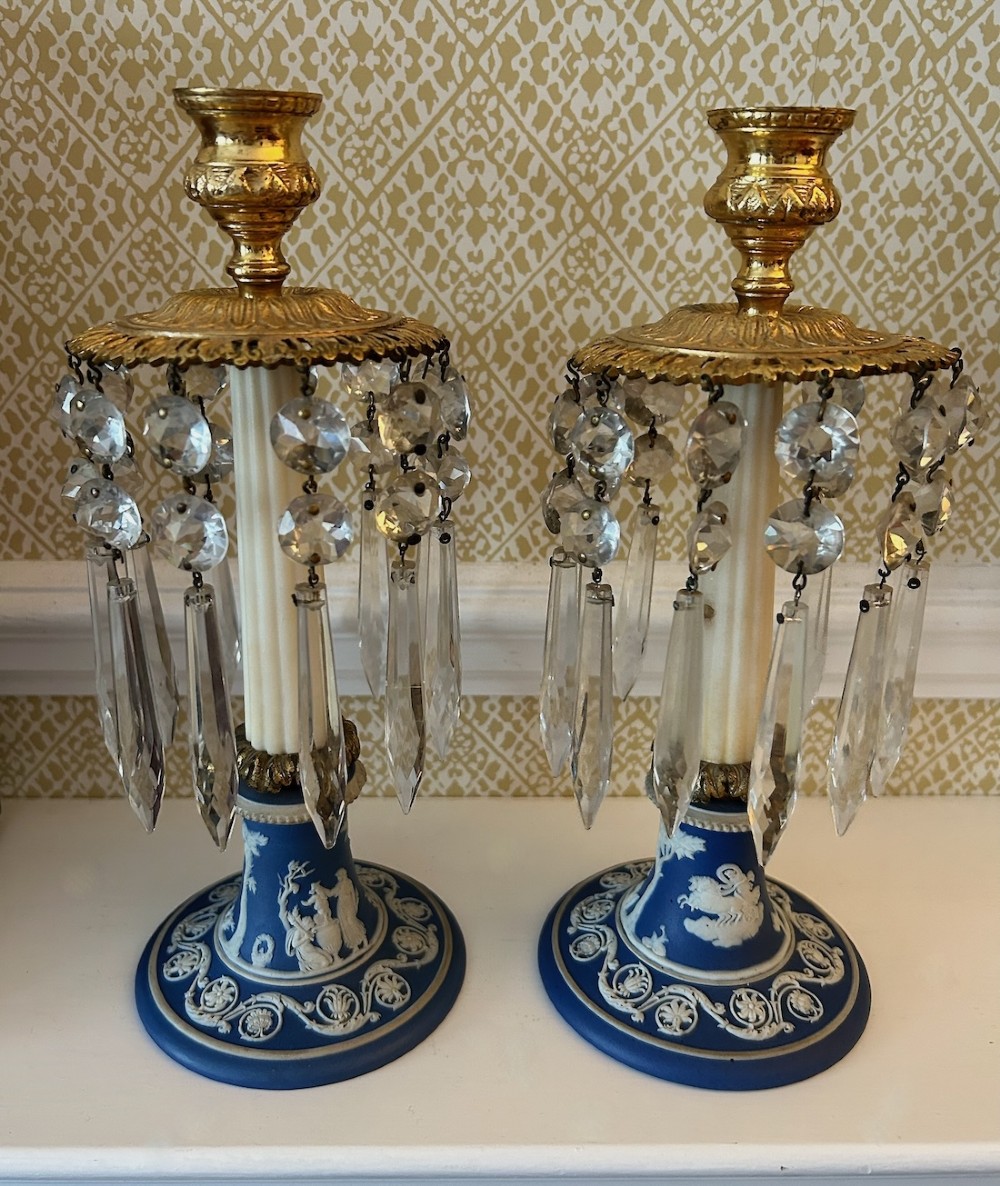 A pair of Victorian candle lustres featuring cobalt blue jasperware bases with white classical reliefs, topped with fluted column shafts, gilt sconces, and hanging cut glass crystal prisms.
