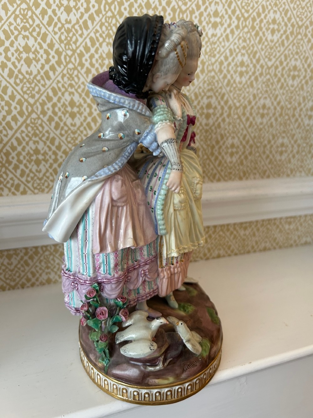 A pair of 19th-century hand-painted Meissen porcelain figurines depicting figures in 18th-century court dress alongside classical urns. View V