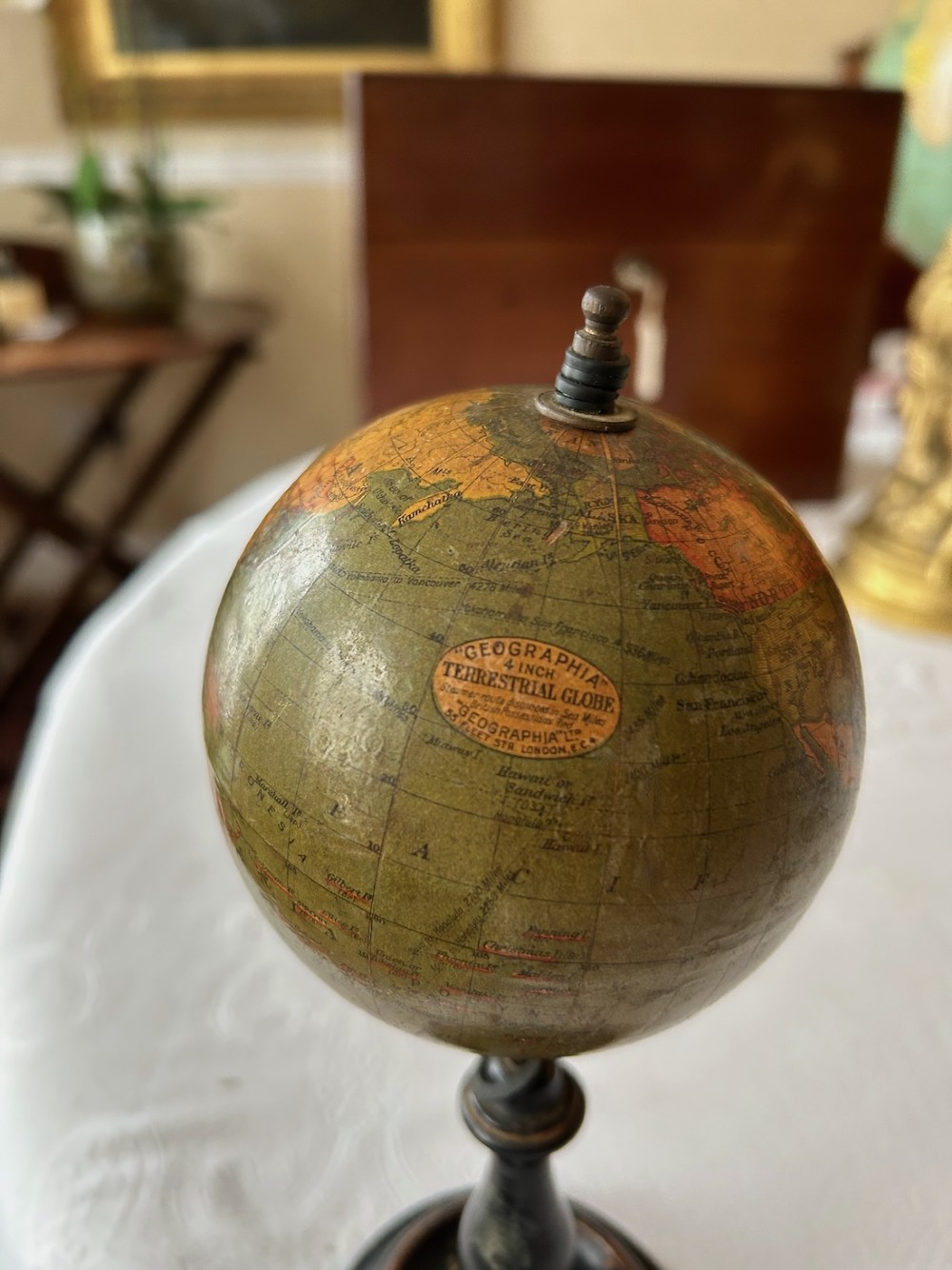 A small 1920s Geographia terrestrial globe featuring printed paper gores set upon a dark turned wooden pedestal stand. View III