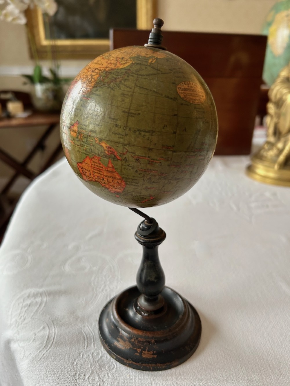 A small 1920s Geographia terrestrial globe featuring printed paper gores set upon a dark turned wooden pedestal stand. View IV