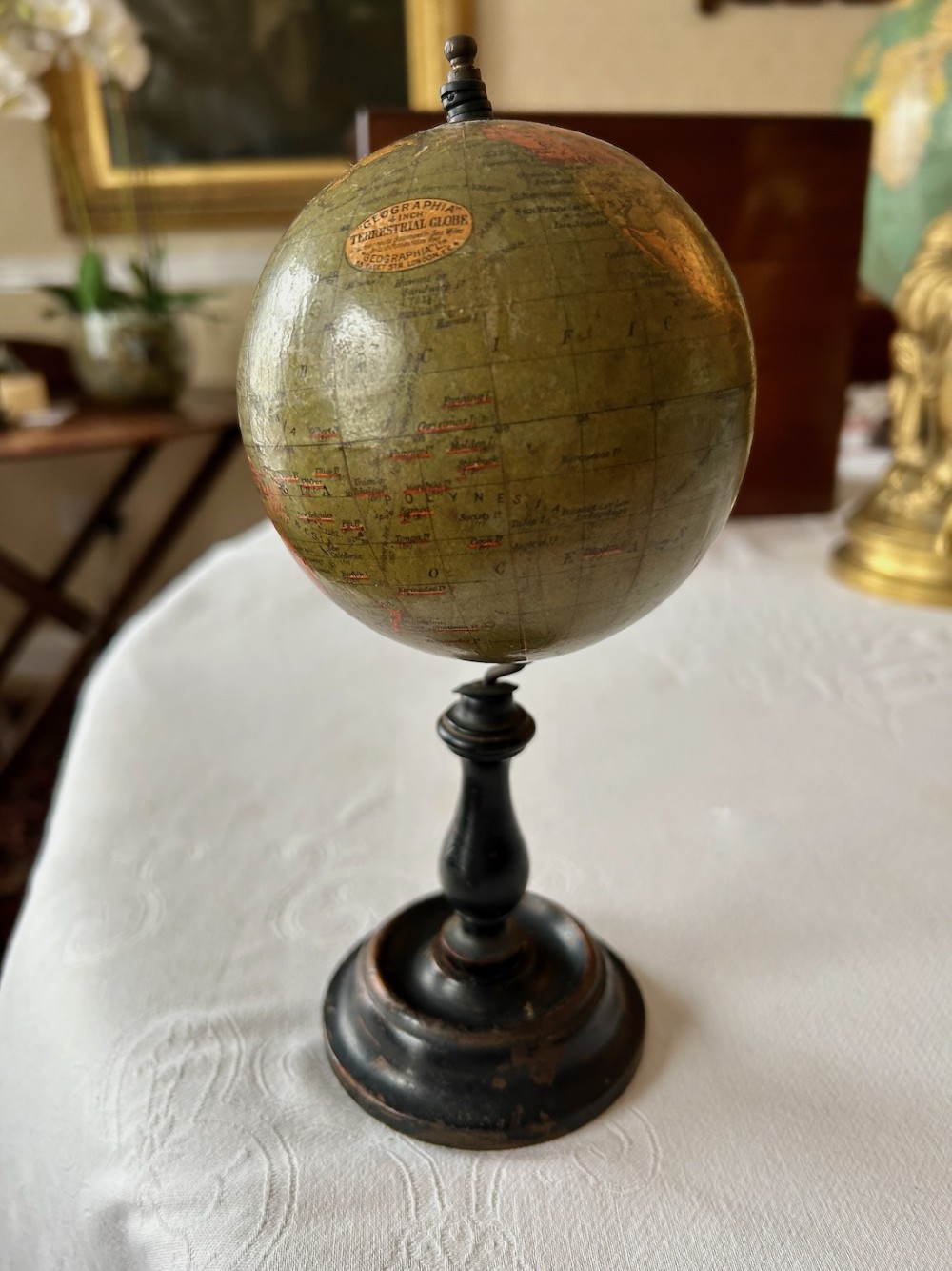 A small 1920s Geographia terrestrial globe featuring printed paper gores set upon a dark turned wooden pedestal stand. View V