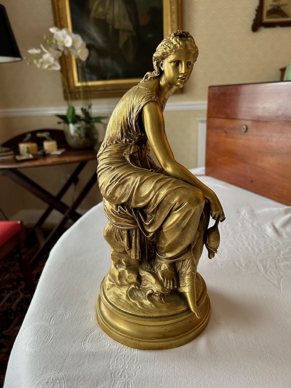 A nineteenth-century French gilt bronze figure depicting a draped classical maiden seated on a circular base. View II