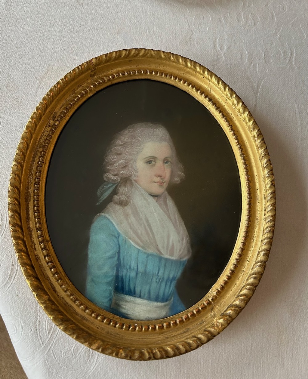 A pair of 18th-century oval pastel portraits depicting a woman in a blue dress and a man in a blue coat, housed in matching giltwood frames. View II