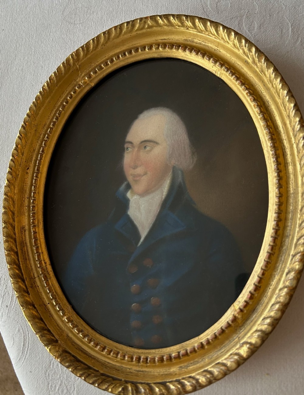 A pair of 18th-century oval pastel portraits depicting a woman in a blue dress and a man in a blue coat, housed in matching giltwood frames. View IV