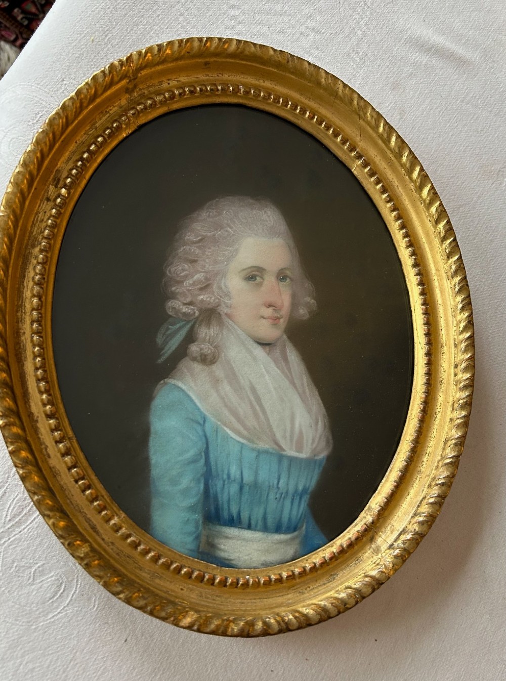 A pair of 18th-century oval pastel portraits depicting a woman in a blue dress and a man in a blue coat, housed in matching giltwood frames. View VI