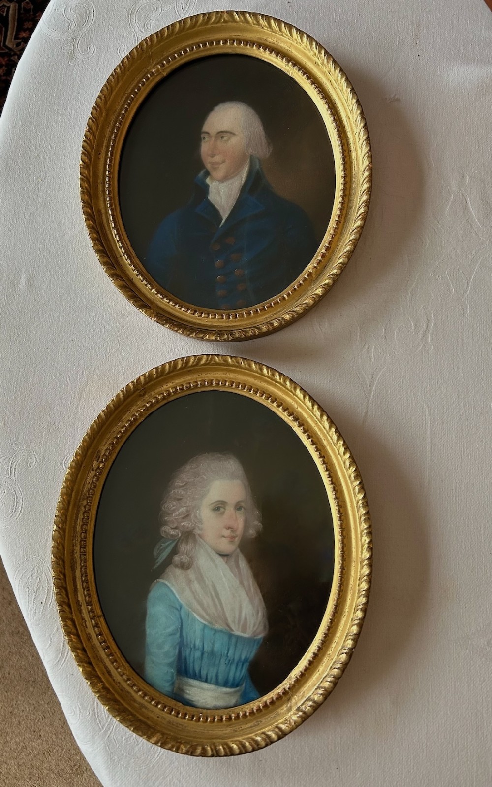 A pair of 18th-century oval pastel portraits depicting a woman in a blue dress and a man in a blue coat, housed in matching giltwood frames. View VII
