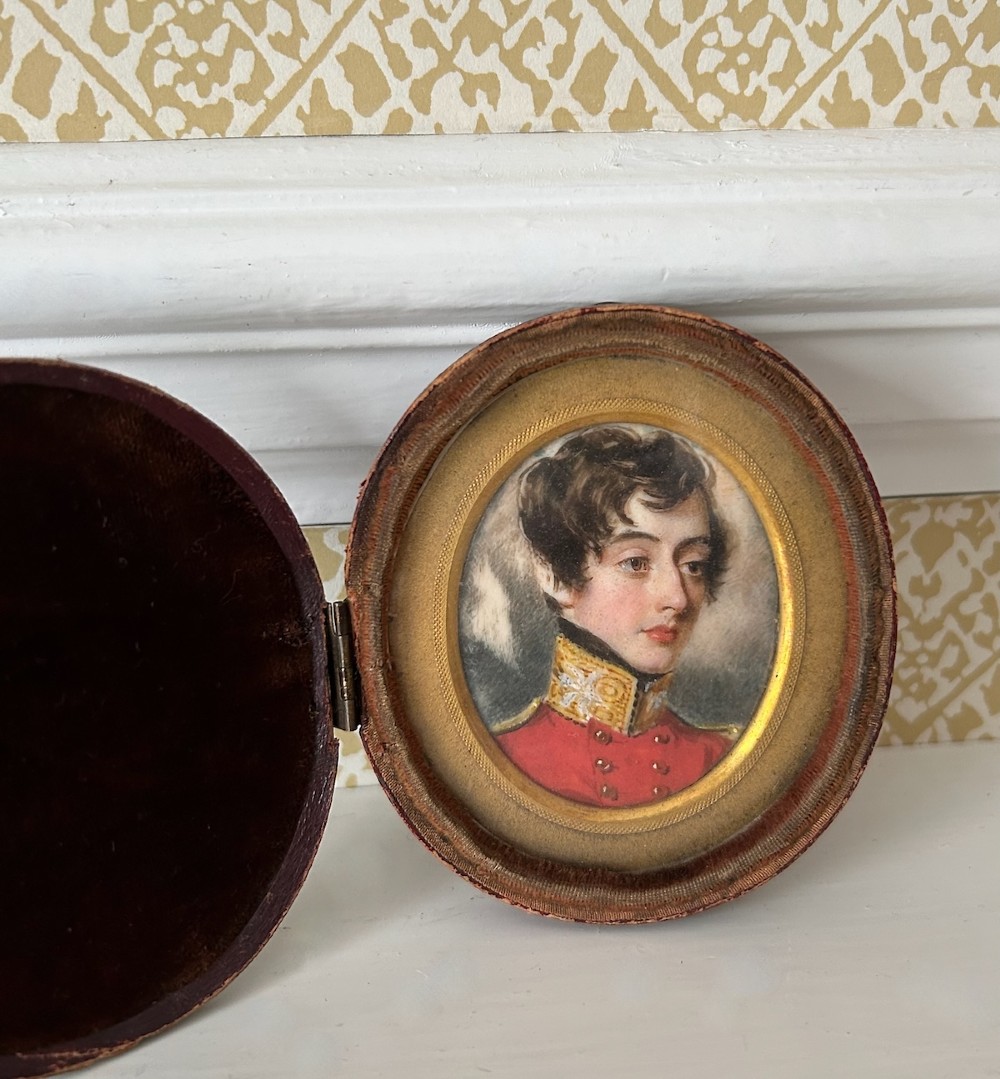 An oval antique portrait miniature depicting a young officer in a scarlet uniform, presented inside an open red leather case. View II
