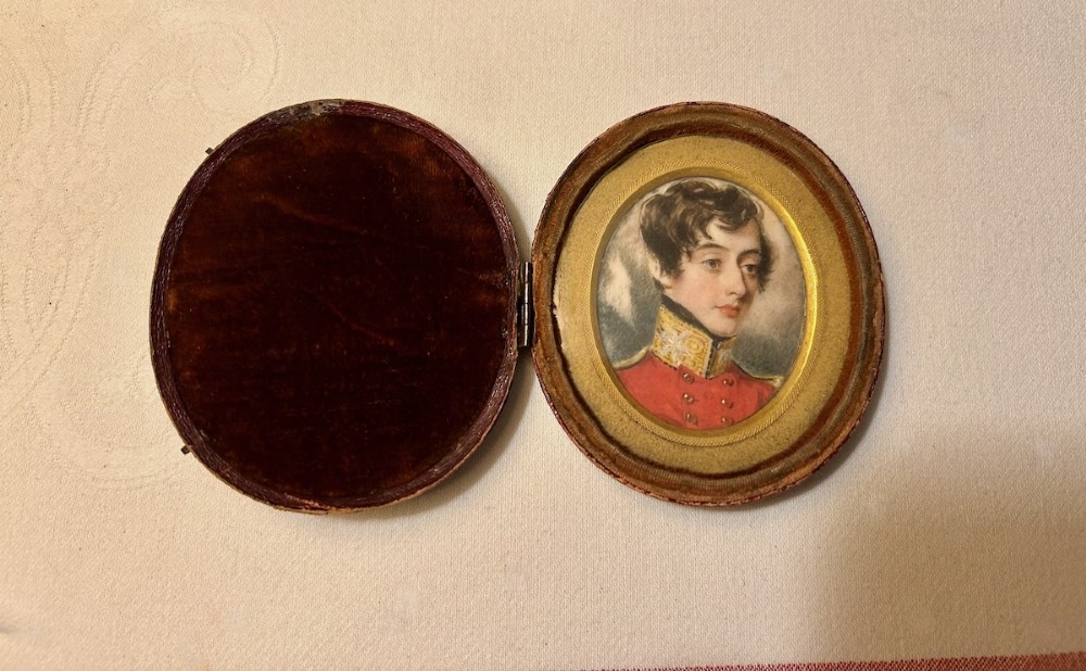 An oval antique portrait miniature depicting a young officer in a scarlet uniform, presented inside an open red leather case. View VIII