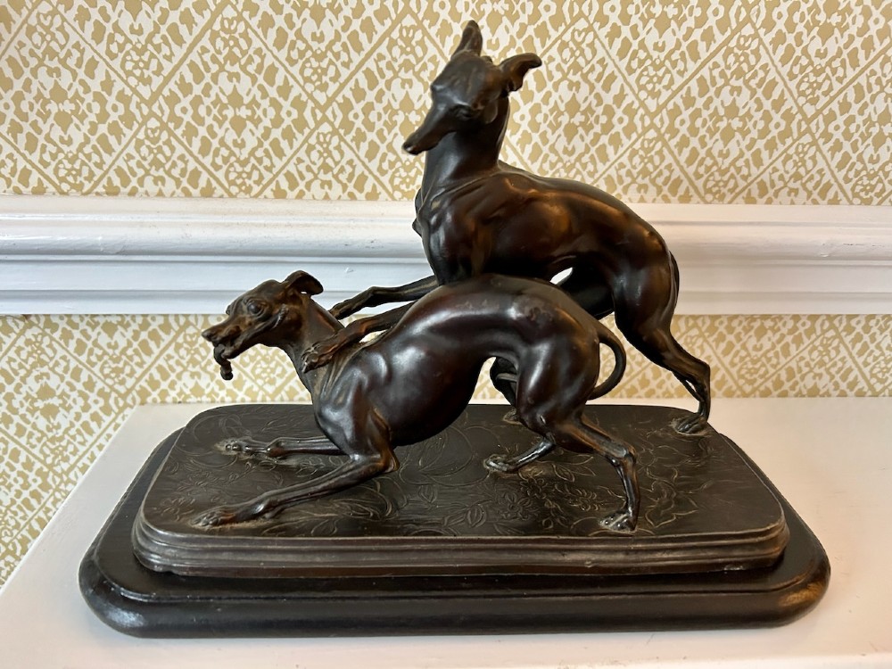 A dark brown patinated spelter sculpture depicting two whippets on a detailed relief base mounted upon a moulded wooden plinth. View IV