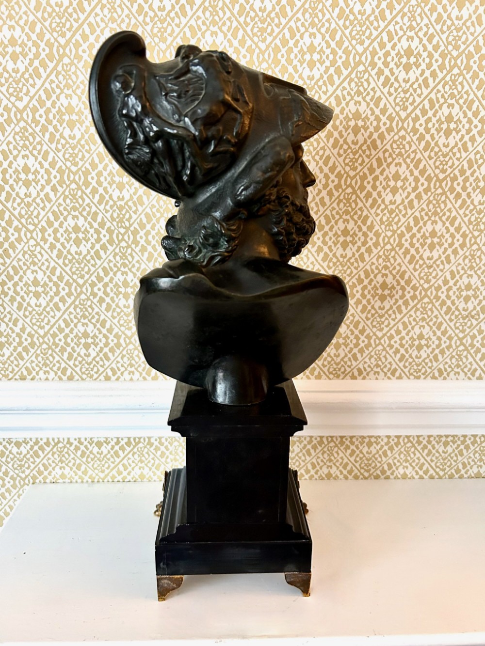 A 19th-century dark bronze bust depicting the classical figure Ajax wearing a crested helmet, mounted on a black marble pedestal with gilt feet. View V