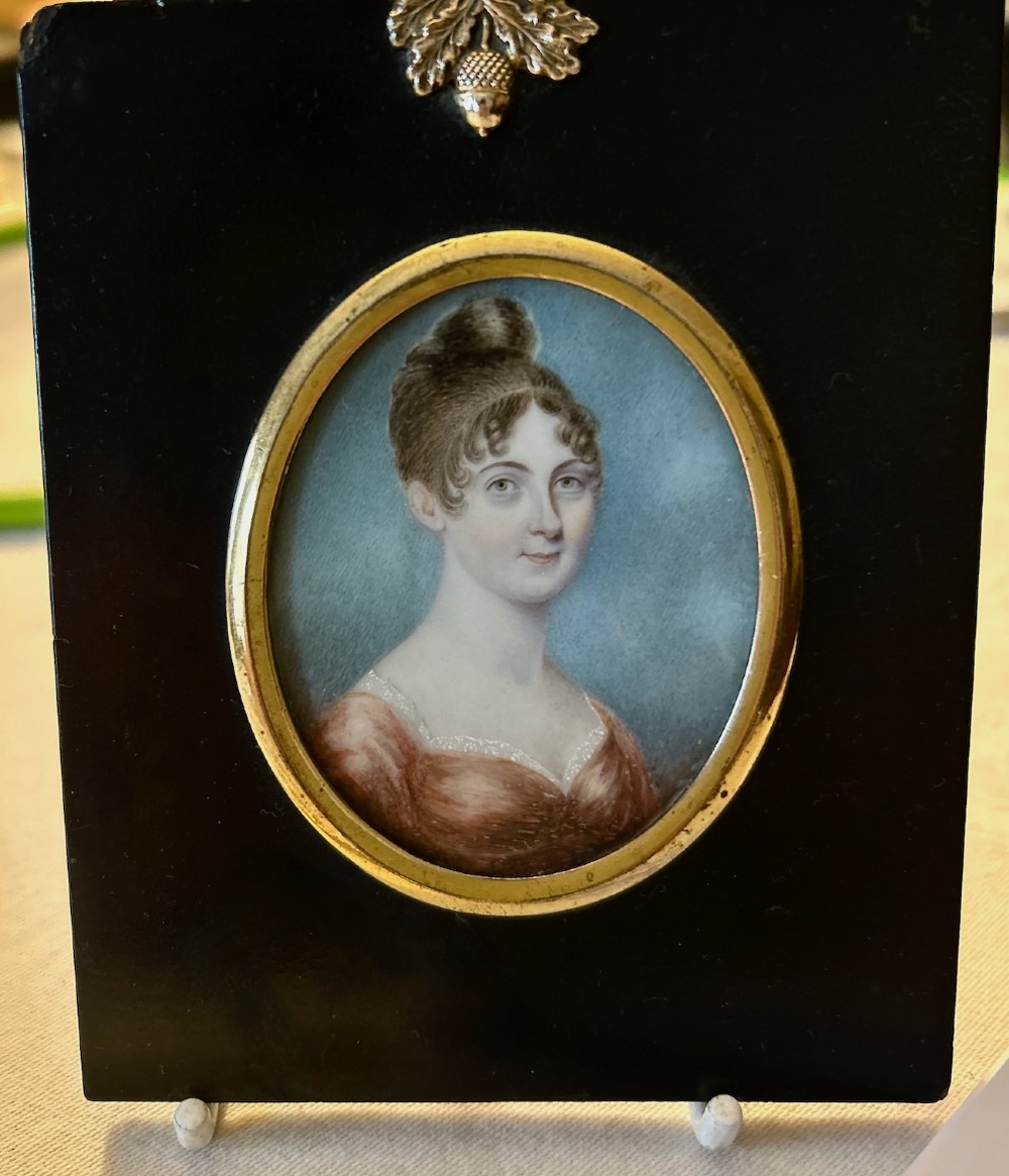 A late 18th-century oval portrait miniature depicting a lady in a red dress, mounted in an ebonised frame with a gilt brass bezel and acorn hanger. View IV
