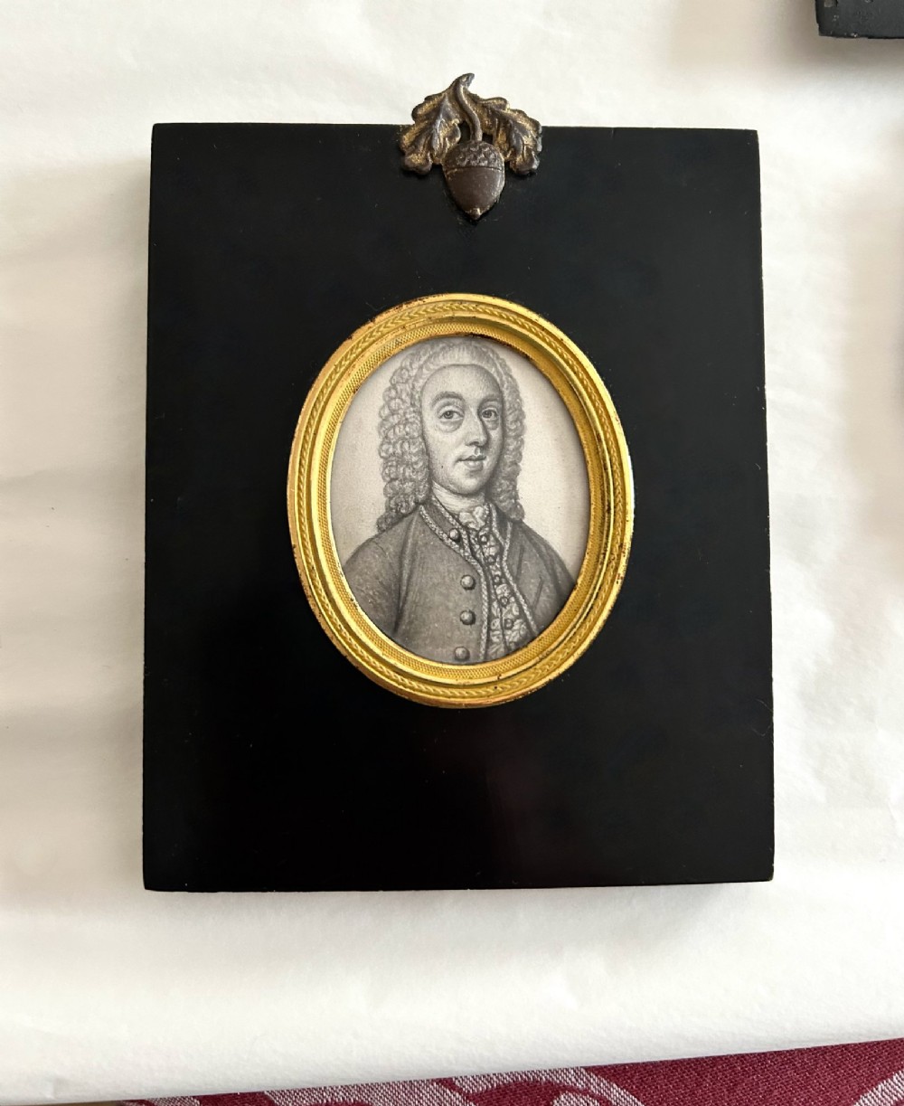 An 18th-century oval monochrome miniature portrait of a gentleman in a period wig, housed in a gilt metal frame mounted on a black ebonised rectangular plaque with an acorn motif hanger. View III
