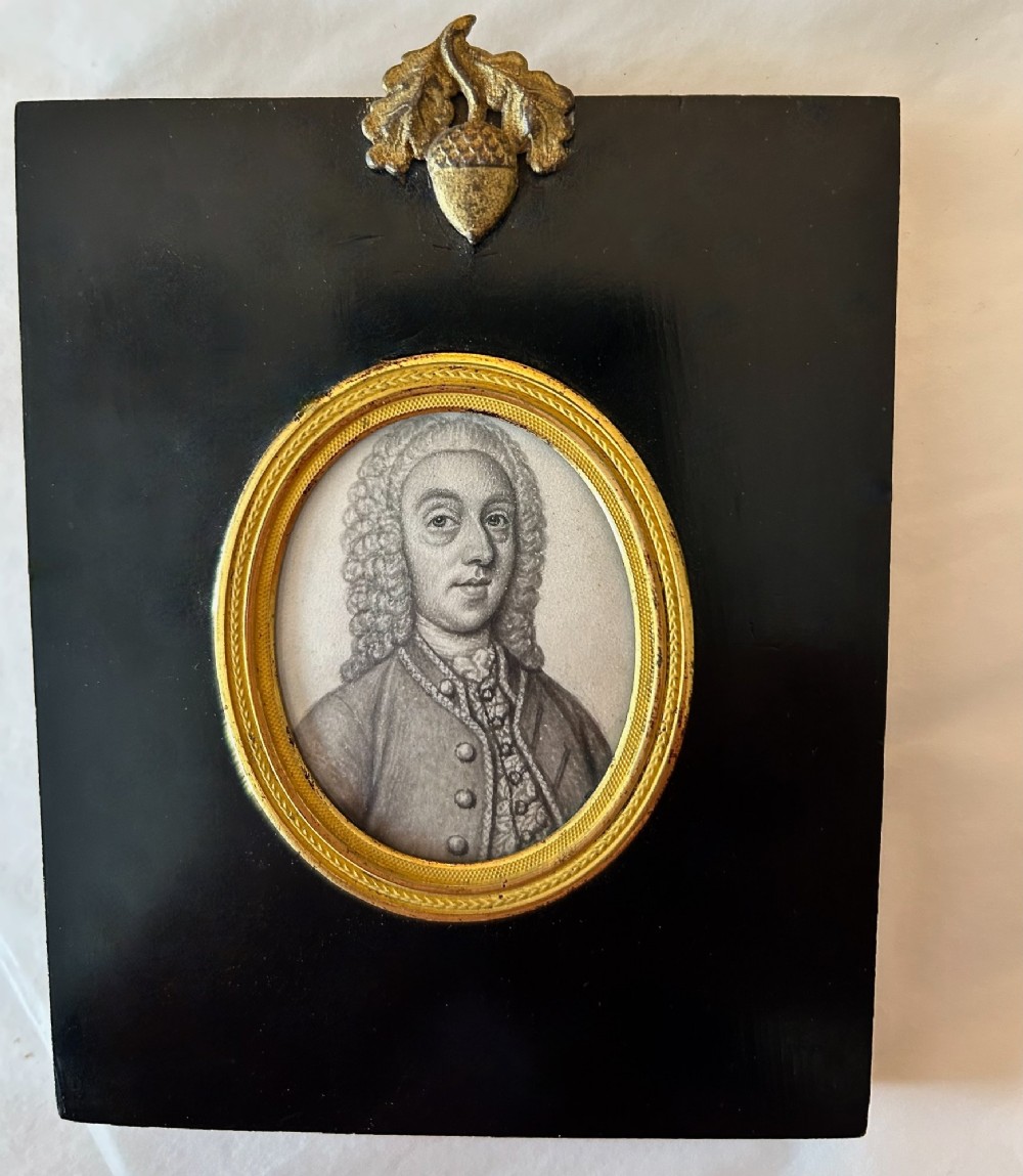An 18th-century oval monochrome miniature portrait of a gentleman in a period wig, housed in a gilt metal frame mounted on a black ebonised rectangular plaque with an acorn motif hanger. View IV
