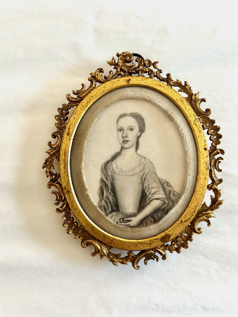 An 18th-century monochrome oval portrait miniature of a lady wearing Georgian dress, set within an ornate carved gilt frame. View II