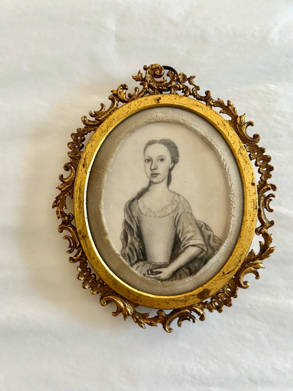 An 18th-century monochrome oval portrait miniature of a lady wearing Georgian dress, set within an ornate carved gilt frame. View III