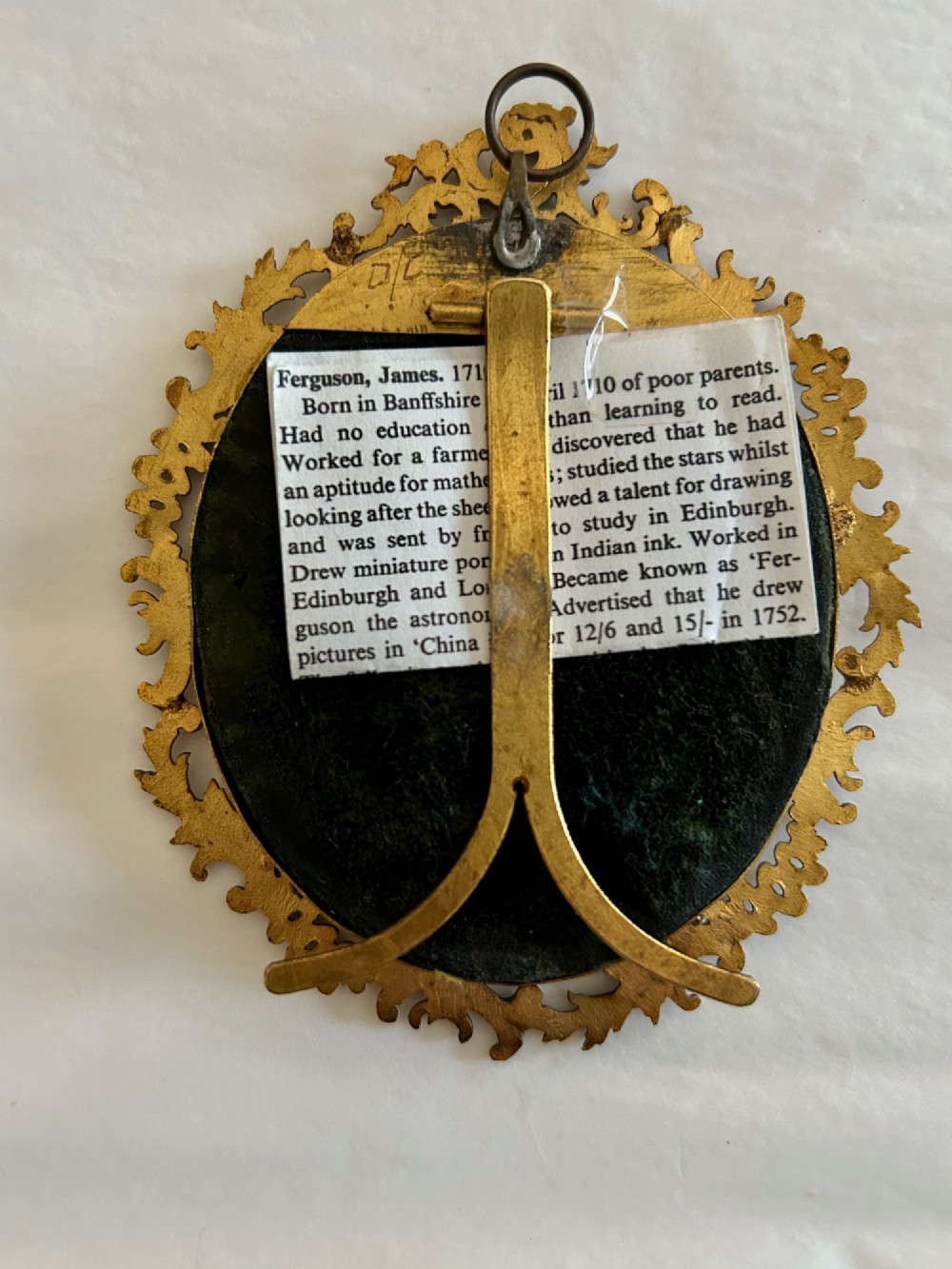 An 18th-century monochrome oval portrait miniature of a lady wearing Georgian dress, set within an ornate carved gilt frame. View IV