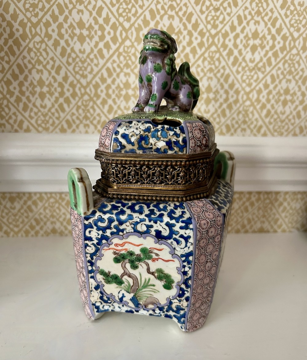 A square 19th-century Chinese porcelain censer featuring a purple foo lion finial on the lid, detailed polychrome enamel floral panels, and blue scrollwork borders. View II