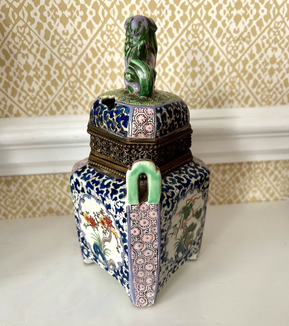A square 19th-century Chinese porcelain censer featuring a purple foo lion finial on the lid, detailed polychrome enamel floral panels, and blue scrollwork borders. View IV