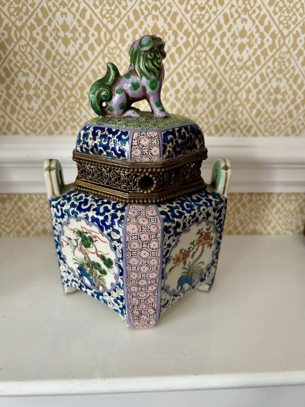A square 19th-century Chinese porcelain censer featuring a purple foo lion finial on the lid, detailed polychrome enamel floral panels, and blue scrollwork borders. View V