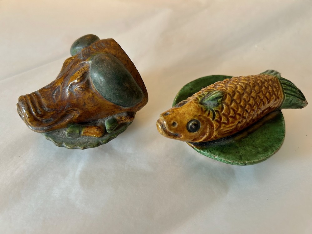 A pair of Chinese Sancai lead-glazed earthenware altar offerings depicting a boars head and a fish on circular dish bases. View IV