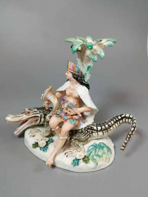 fig 1. An 18th-century Chelsea polychrome porcelain statuette depicting an allegorical female figure seated on an alligator beside a palm tree.