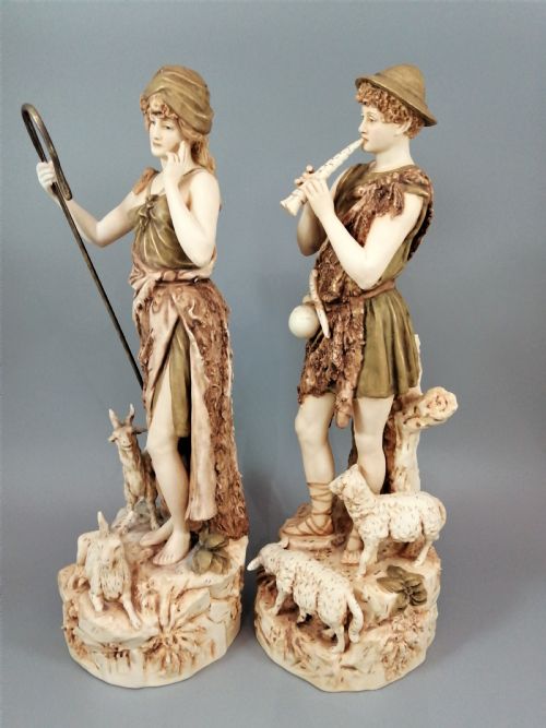 fig 2. A pair of antique Royal Dux porcelain statuettes depicting a shepherdess holding a staff beside goats and a shepherd playing a pipe beside sheep.