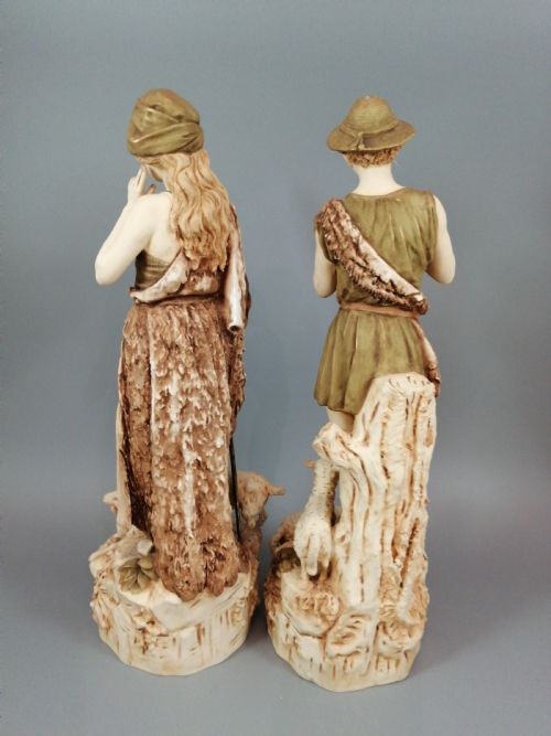 fig 3. A pair of antique Royal Dux porcelain statuettes depicting a shepherdess holding a staff beside goats and a shepherd playing a pipe beside sheep.
