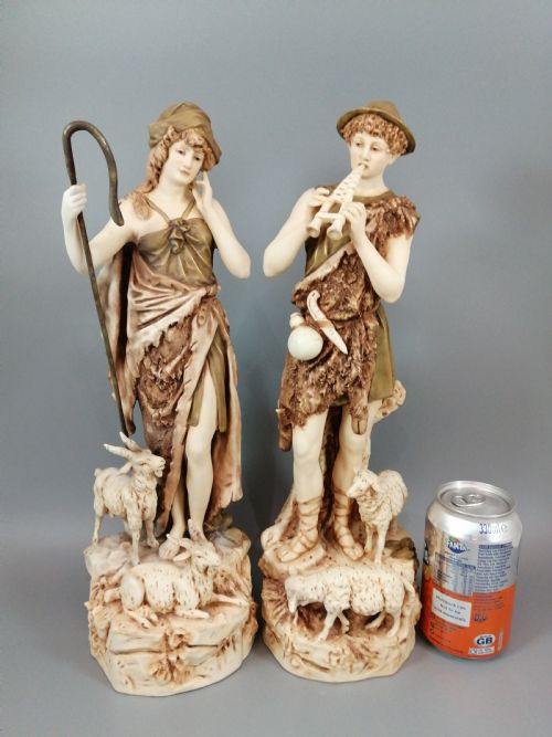fig 6. A pair of antique Royal Dux porcelain statuettes depicting a shepherdess holding a staff beside goats and a shepherd playing a pipe beside sheep.