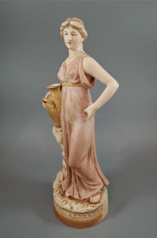 fig 1. A Royal Dux porcelain statuette of a classical maiden in a draped dusty pink gown holding an earthenware jug.