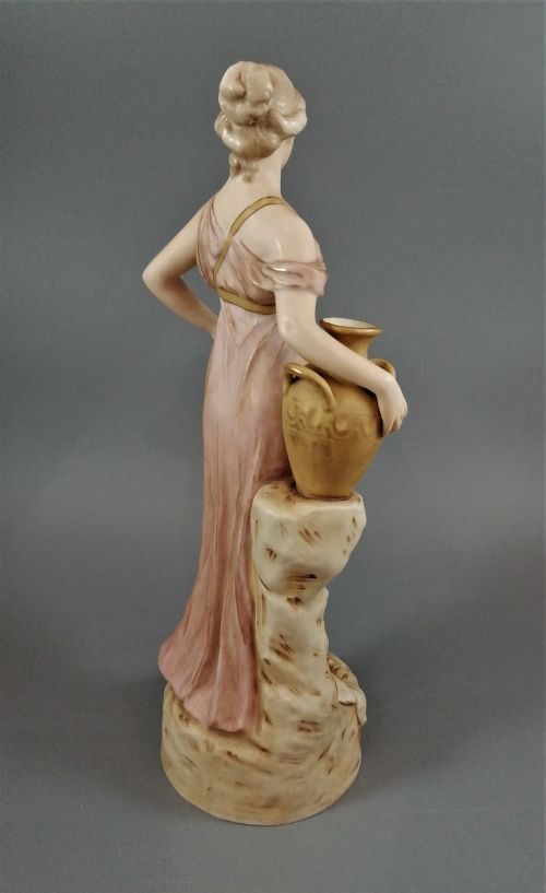 fig 4. A Royal Dux porcelain statuette of a classical maiden in a draped dusty pink gown holding an earthenware jug.