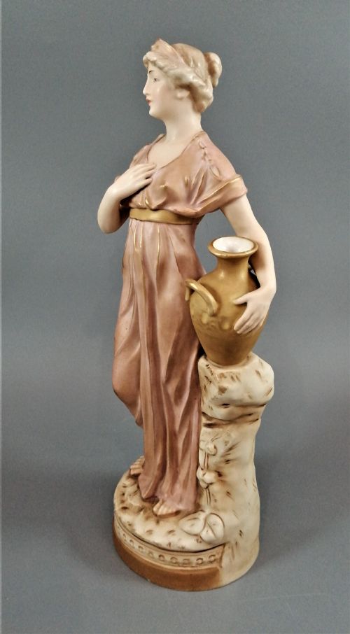 fig 2. An antique Royal Dux porcelain figurine depicting a woman in a draped pink gown holding a gilded water jug.