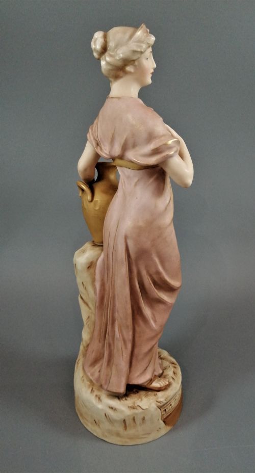 fig 3. An antique Royal Dux porcelain figurine depicting a woman in a draped pink gown holding a gilded water jug.
