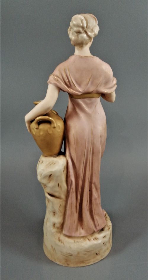fig 4. An antique Royal Dux porcelain figurine depicting a woman in a draped pink gown holding a gilded water jug.