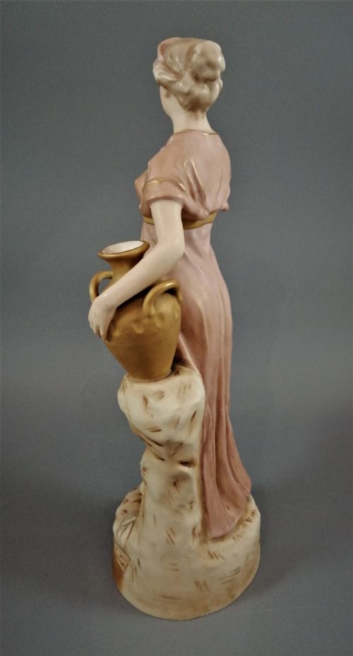 fig 5. An antique Royal Dux porcelain figurine depicting a woman in a draped pink gown holding a gilded water jug.