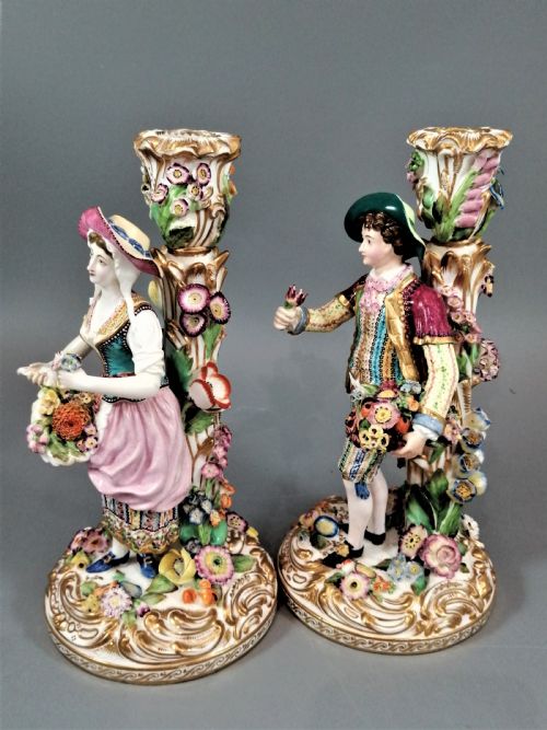 fig 1. A pair of hand-painted Minton porcelain figural candlesticks featuring a male and female figure in colourful traditional dress with floral motifs and gilded scroll bases.
