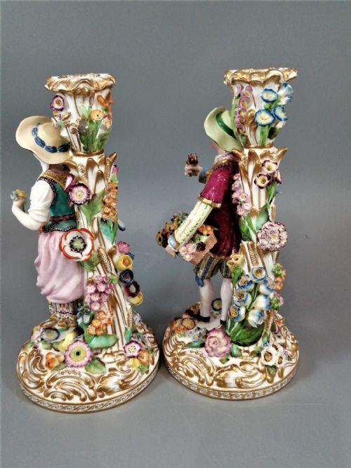fig 2. A pair of hand-painted Minton porcelain figural candlesticks featuring a male and female figure in colourful traditional dress with floral motifs and gilded scroll bases.