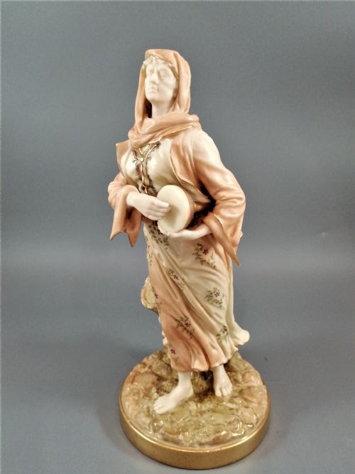 fig 1. A late Victorian Royal Worcester porcelain figurine depicting a standing female musician in draped robes holding a hand drum.