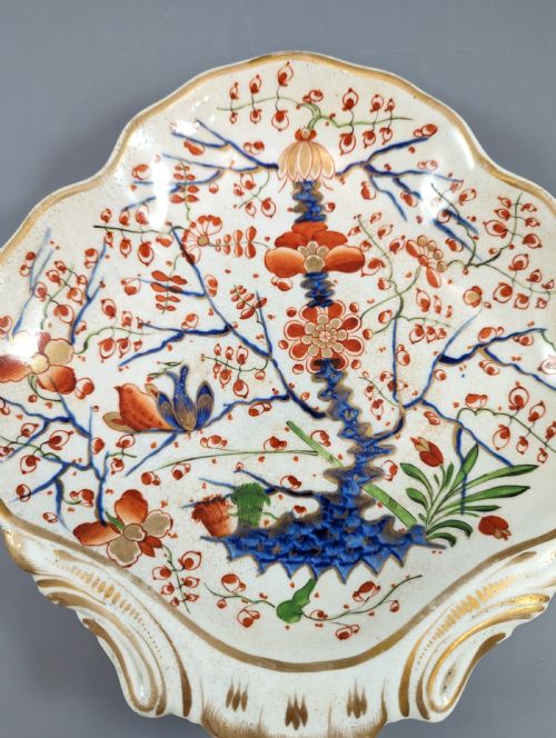 fig 2. An antique shell-shaped porcelain plate featuring hand-painted Kakiemon-style motifs of two quails beneath flowering branches with gilt highlights.