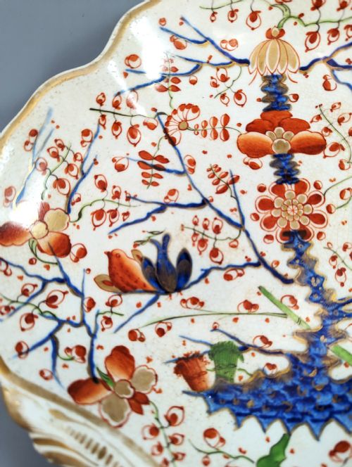 fig 3. An antique shell-shaped porcelain plate featuring hand-painted Kakiemon-style motifs of two quails beneath flowering branches with gilt highlights.