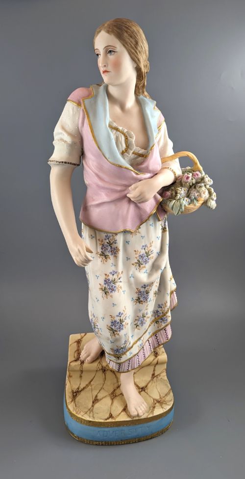 fig 2. A Victorian coloured Parian porcelain figure depicting a draped female figure holding a basket of flowers on a faux-marble painted base.