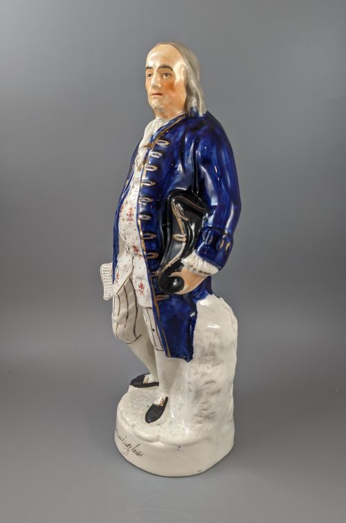 fig 2. A Victorian Staffordshire earthenware figure of Benjamin Franklin standing in a cobalt blue coat and holding a tricorn hat, set on a pedestal inscribed Washington.