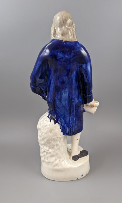 fig 4. A Victorian Staffordshire earthenware figure of Benjamin Franklin standing in a cobalt blue coat and holding a tricorn hat, set on a pedestal inscribed Washington.