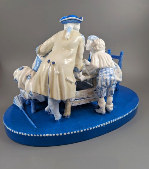 fig 3. Late 19th-century French blue and white glazed porcelain figurine group depicting four figures gathered around a table fortune-telling on an oval blue base.