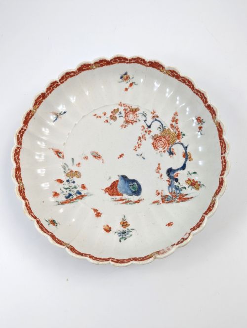 fig 1. A circular fluted soft-paste porcelain dish decorated with the Kakiemon quail pattern in iron-red, blue, and gold enamels on a white ground.