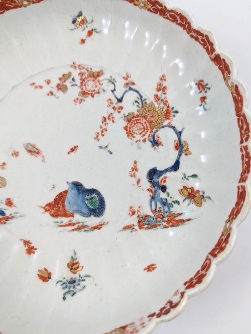 fig 3. A circular fluted soft-paste porcelain dish decorated with the Kakiemon quail pattern in iron-red, blue, and gold enamels on a white ground.