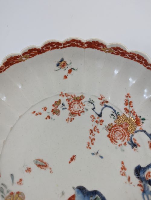 fig 4. A circular fluted soft-paste porcelain dish decorated with the Kakiemon quail pattern in iron-red, blue, and gold enamels on a white ground.