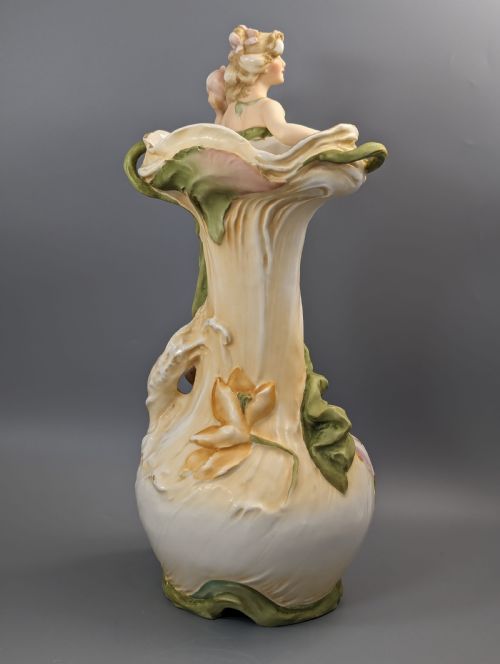 fig 4. An Art Nouveau Royal Dux porcelain vase depicting a draped water nymph holding a seashell against flowing foliage in cream, olive green, and soft pink shades.