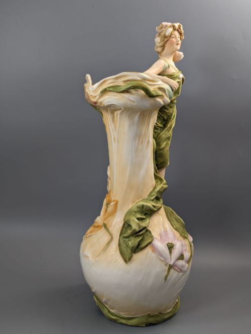 fig 5. An Art Nouveau Royal Dux porcelain vase depicting a draped water nymph holding a seashell against flowing foliage in cream, olive green, and soft pink shades.